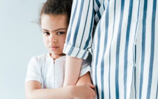 Child Refusing Visitation with a Parent in Los Angeles California portrayed by a child hiding behind her mother.